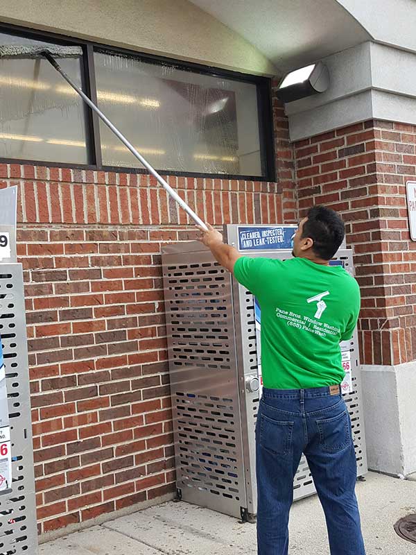 man cleaning store window