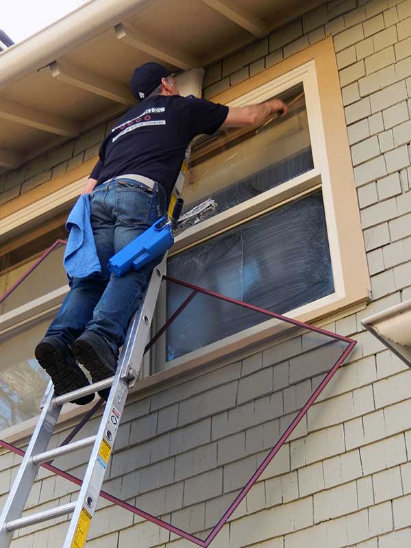 man on ladder cleaning window